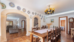 Un comedor con una mesa de madera larga y sillas, rodeado de arcos y platos decorativos en las paredes.
