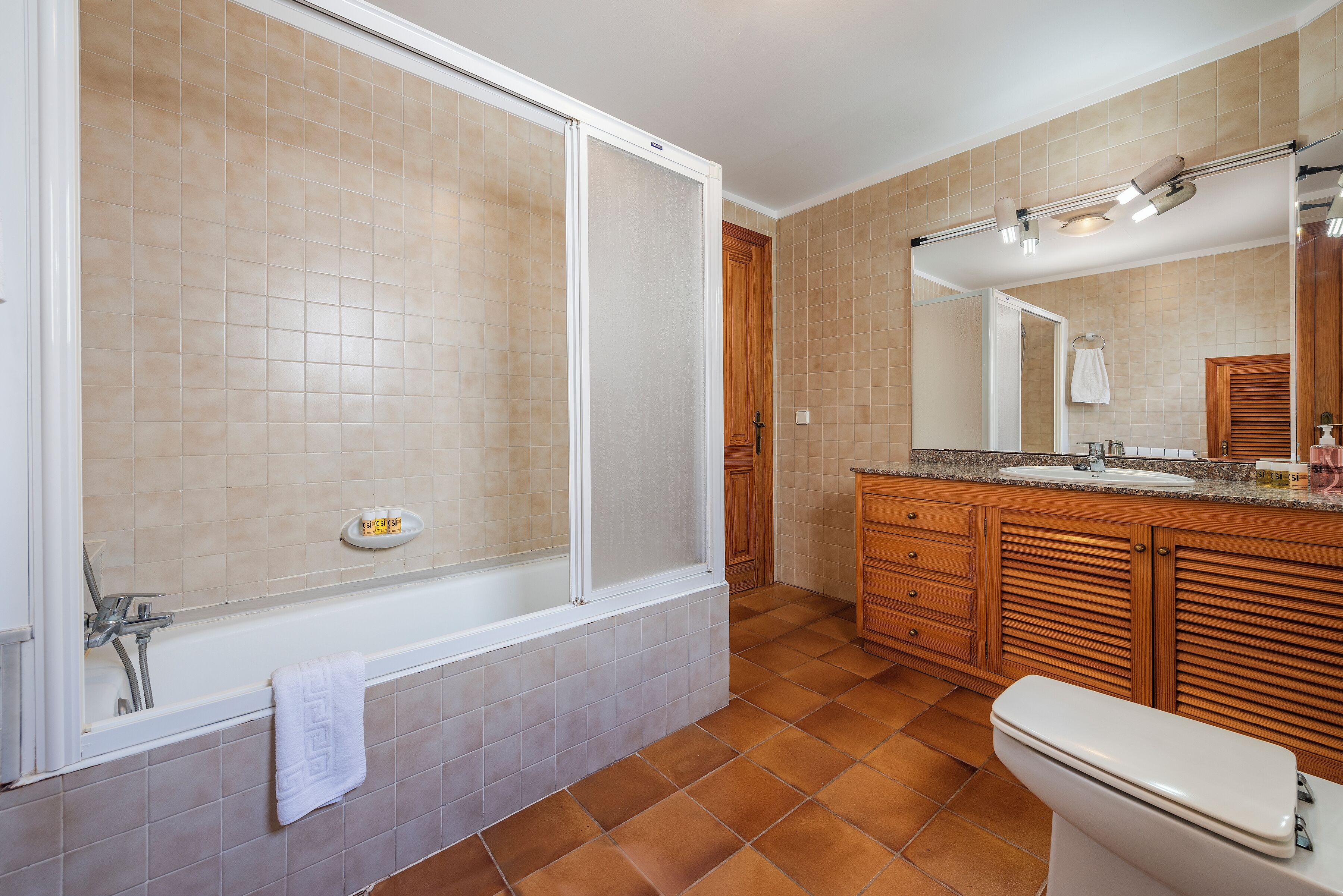 A bathroom with a bathtub, toilet, vanity, and a mirror.