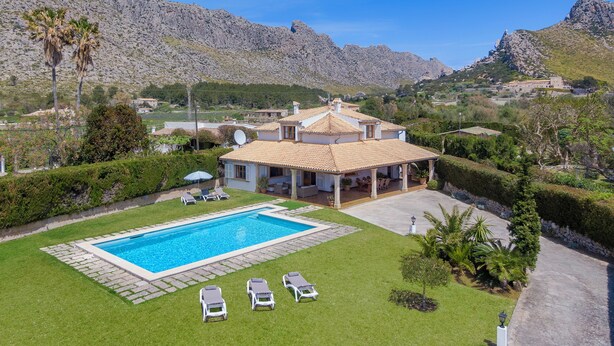 Una villa con piscina, sillas de descanso y zona de patio.