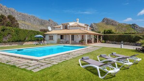 Una villa con piscina, sillas de descanso y un patio.