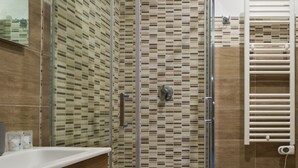 A modern bathroom with a glass shower enclosure, a white sink, and a towel rack. - Central Station Housing Apartments (NAPOLI)