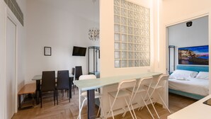 A compact room with a dining table and chairs, a bed with a view, and a decorative wall panel. - Central Station Housing Apartments (NAPOLI)