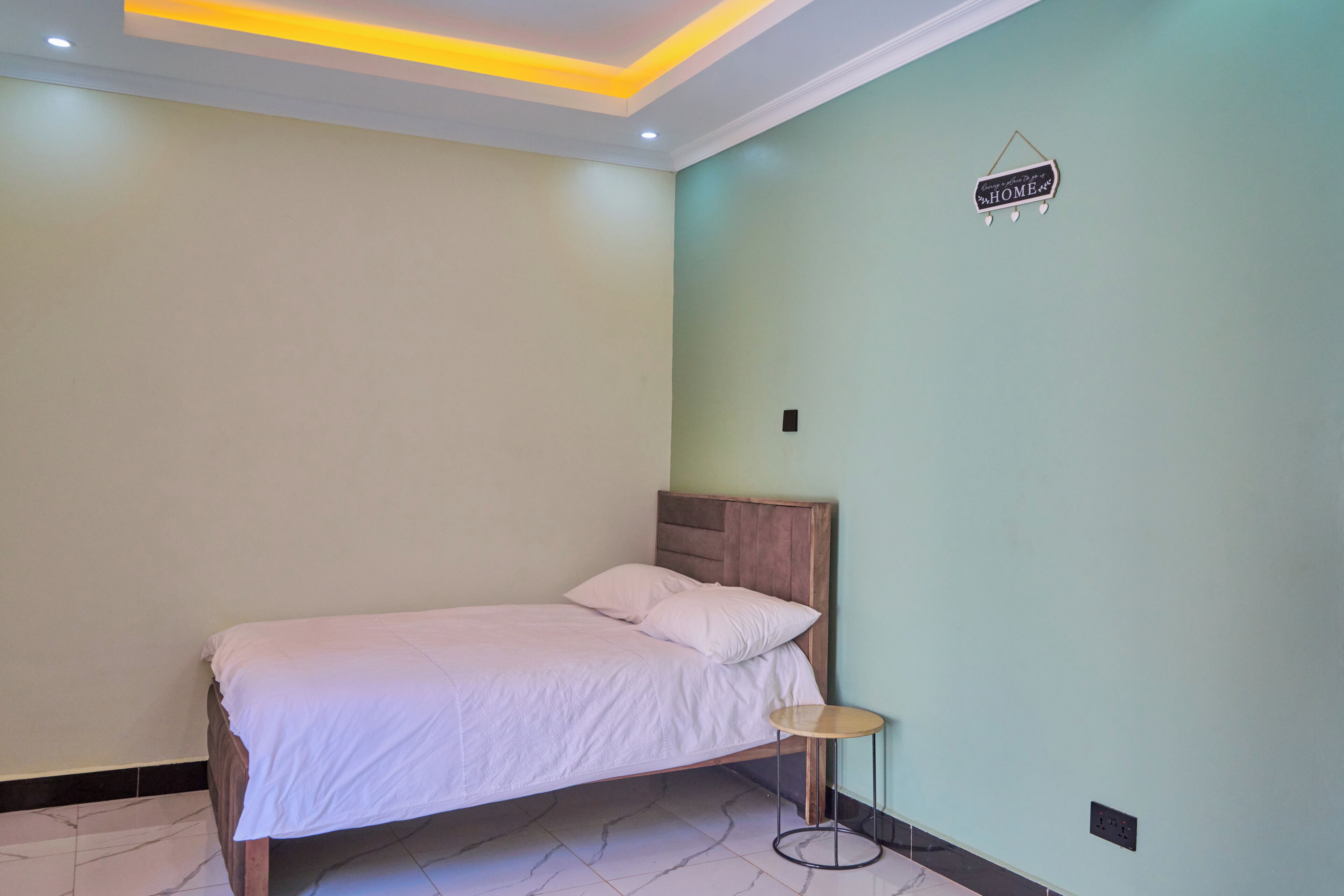 A bedroom with a bed, a small round table, and a sign on the wall.