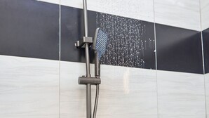 A modern shower with a rain showerhead and handheld control. - Freetown Resort-Gulu (Gulu)