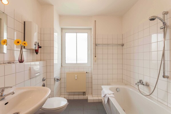 Ein Badezimmer mit Waschbecken, Toilette, Badewanne und einem Fenster.