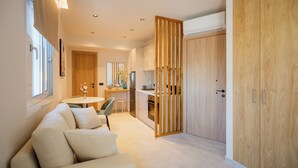 A modern kitchen with wooden cabinets, a dining area with a table and chairs, and a sofa in a living area. - PORT VIEW (Zakynthos)