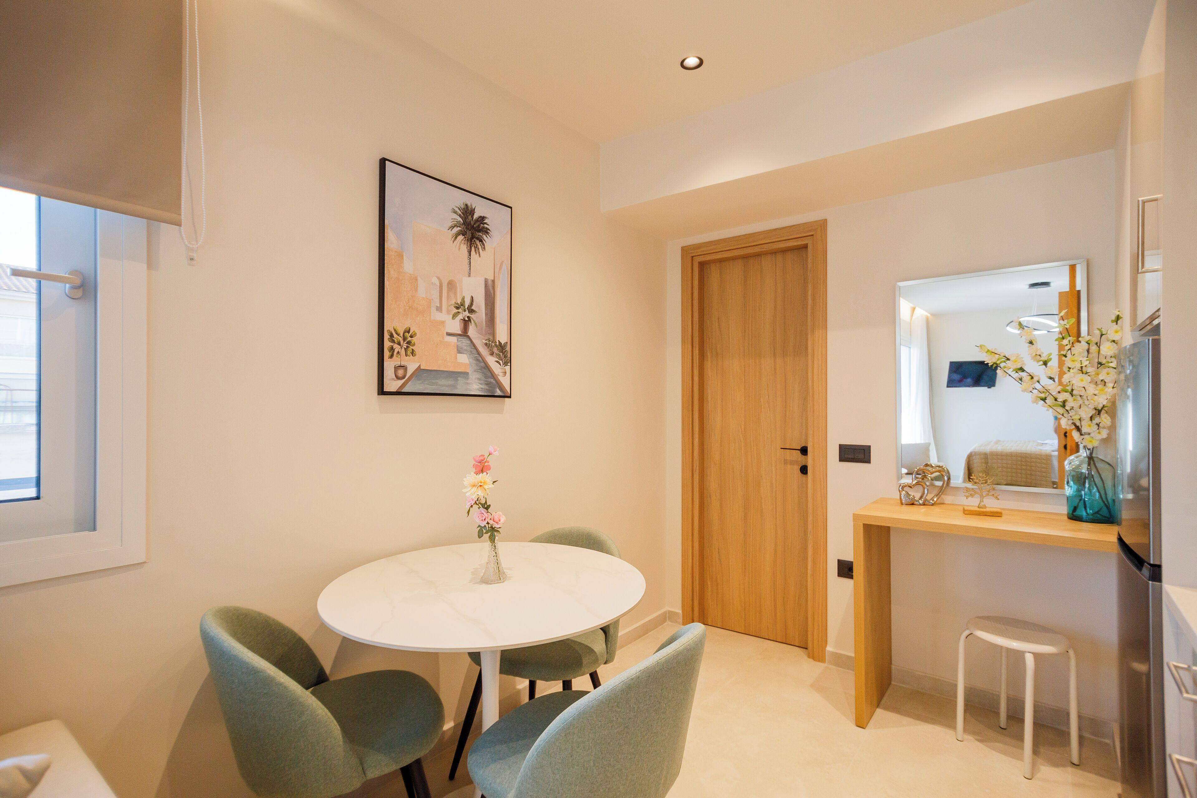 A modern dining area with a round table and four chairs, a wooden door, and a small stool.