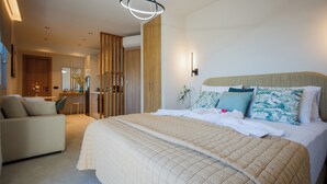 A modern hotel bedroom with a large bed, a sofa, a desk, and a mirror. - PORT VIEW (Zakynthos)