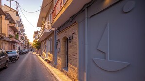 A narrow street lined with parked cars and buildings with balconies and awnings. - PORT VIEW (Zakynthos)