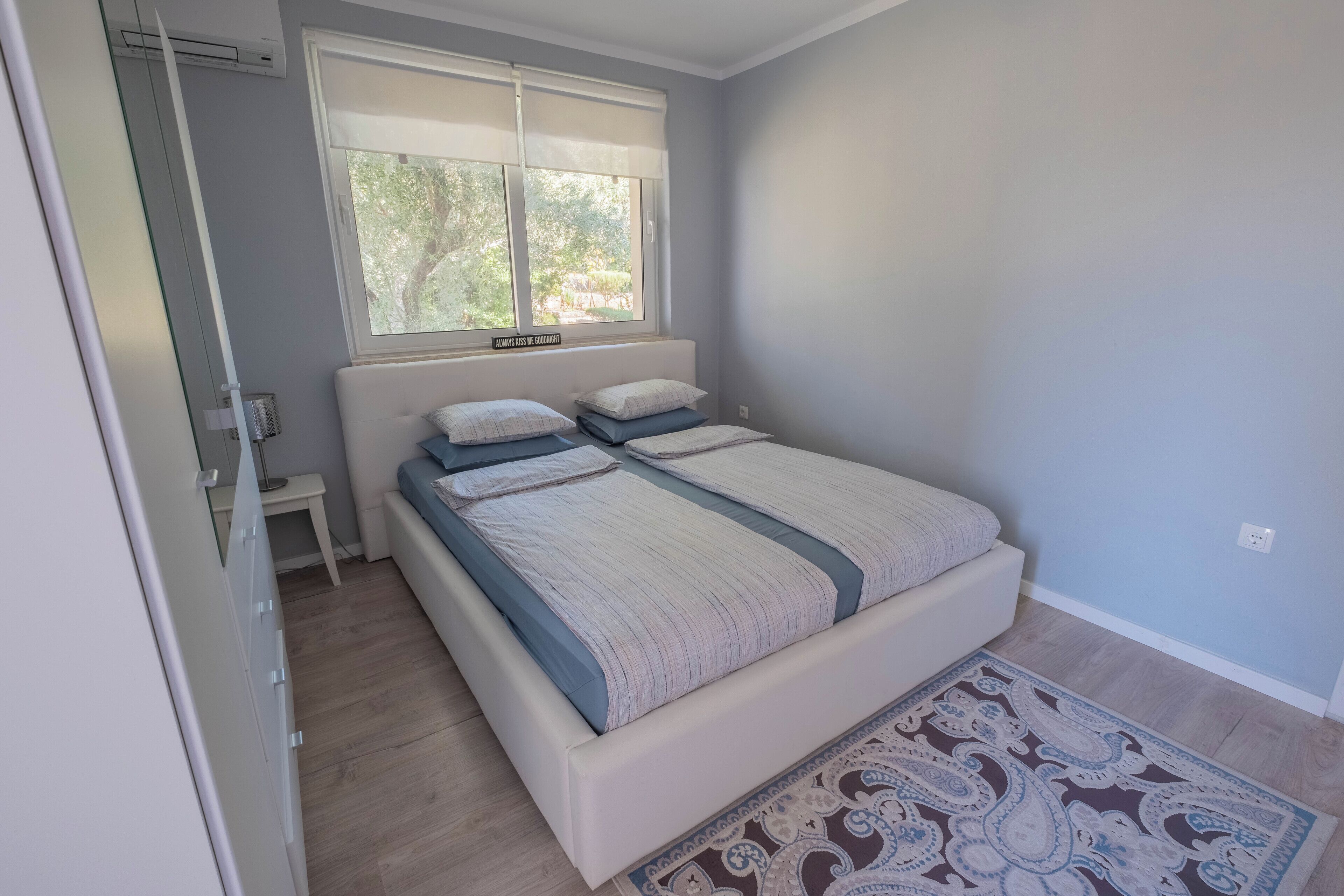 A bedroom with a bed, a window, a bedside table, and a wardrobe.