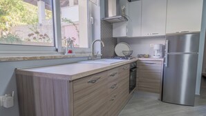 Una cocina moderna con armarios de madera, un refrigerador de acero inoxidable y un ventanal con vistas a la vegetación.