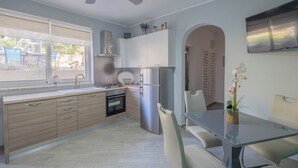 Una cocina moderna con estufa a gas, refrigerador de acero inoxidable y comedor con mesa y sillas de vidrio.
