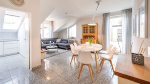 Ein modernes Wohnzimmer mit Essbereich, einer Couch, einem Holzschrank und einer Wanduhr.