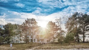 A beachfront property with a modern building, sandy beach, and surrounding trees. - Vacation apartment 7 in the Villa Vogue Binz for 4 persons, sea view, on the street (Binz)