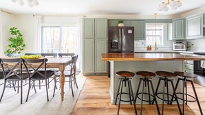 Cozinha moderna com ilha central, banquetas de bar e área de refeições com mesa e cadeiras.