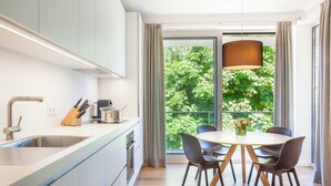 A modern kitchen with a large window, a dining area with chairs, and a table. - Vacation apartment Greta`s Beach Home in the Villa Vogue for 4 persons, Meeresbl (Binz)