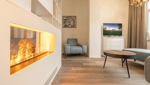 A modern living room with a fireplace, a television, and a dining area. - Vacation apartment Sabei Villa Metropol, fireplace, sauna, close to the beach, beach chair (Binz)