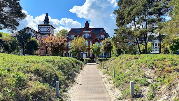 A pathway leading to a large, traditional-style building with multiple windows and a prominent tower. - Comfort apartment Wabi Sabi in the Villa Glückspilz for 4 people, beach location (Binz)