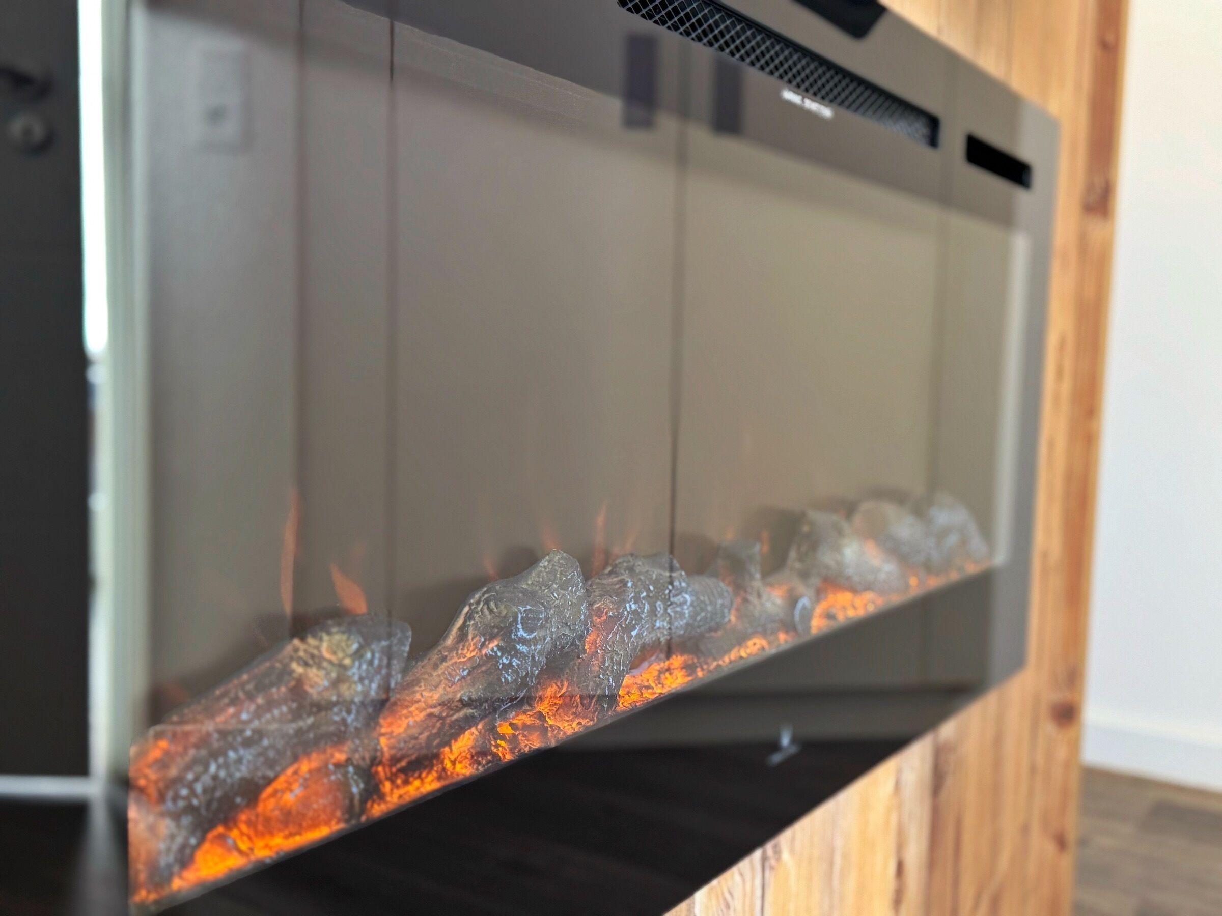 A fireplace with a glass front, displaying burning logs.