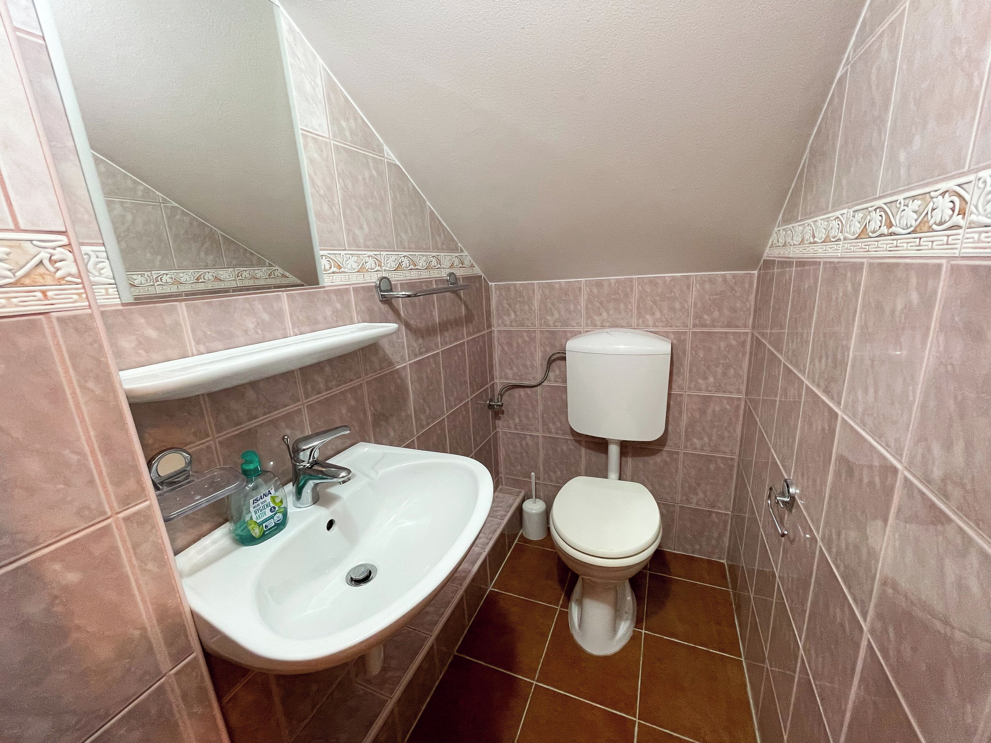 Een badkamer met een wastafel, spiegel, toilet en decoratieve tegels.