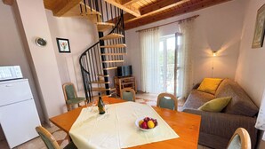 A dining area with a wooden table, chairs, a spiral staircase, a sofa, and a television. - Apartman Villa Ljiljana 9 (Jadranovo)