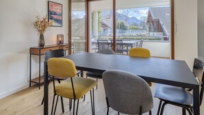 Un espace de restauration moderne, doté d’une grande table, de plusieurs chaises et offrant une vue sur les montagnes grâce à de larges fenêtres.