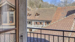Un bâtiment traditionnel, avec un toit en tuiles et des fenêtres en bois, vu depuis un balcon doté d’une rambarde en métal.