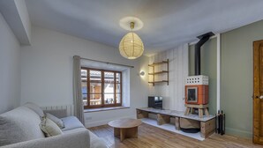 Un salon chaleureux avec un canapé, une table basse ronde, un téléviseur, une cheminée et une porte en bois.