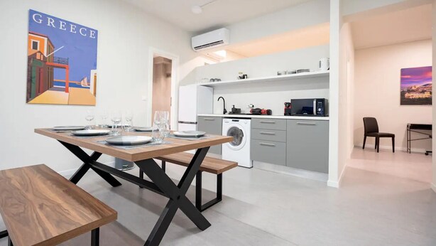 Une cuisine moderne équipée d’un lave-linge, d’un four à micro-ondes et d’un évier. On y trouve également un coin repas avec une table et des bancs en bois.
