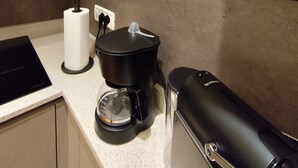 A kitchen with a coffee maker, a paper towel holder, and a wall sign advertising coffee. - La Casa di Lollo - Everything You Need Just Steps from the City Center (Firenze)