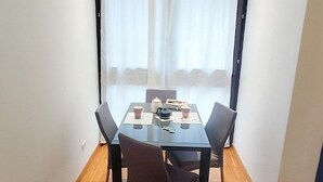 A dining area with a glass table, four chairs, and a window with curtains. - La Casa di Lollo - Everything You Need Just Steps from the City Center (Firenze)