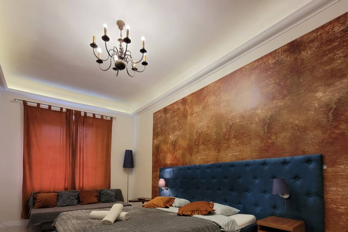 Une chambre à coucher avec un grand lit, une table de chevet, une lampe et un lustre.
