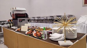 A buffet setup with various dishes, a coffee machine, and stacked plates. - Me Time Residence  (Enugu)