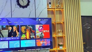 A modern living room with a flat-screen TV mounted on a marble wall, displaying various streaming services. - Me Time Residence (Enugu)