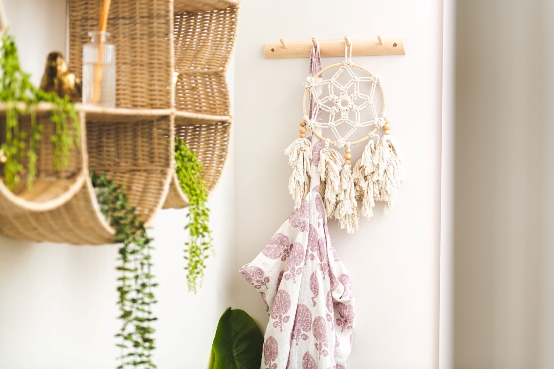 A room with a macrame dreamcatcher, wicker baskets, and hanging plants.