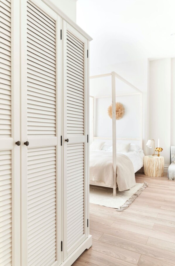 A bedroom with a four-poster bed, a large wardrobe, and a round wall decoration.