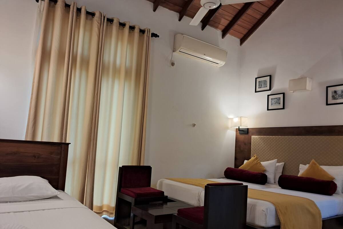 Hotellihuone, jossa on sänky, työpöytä, tuoli, ilmastointilaite ja kattotuuletin.