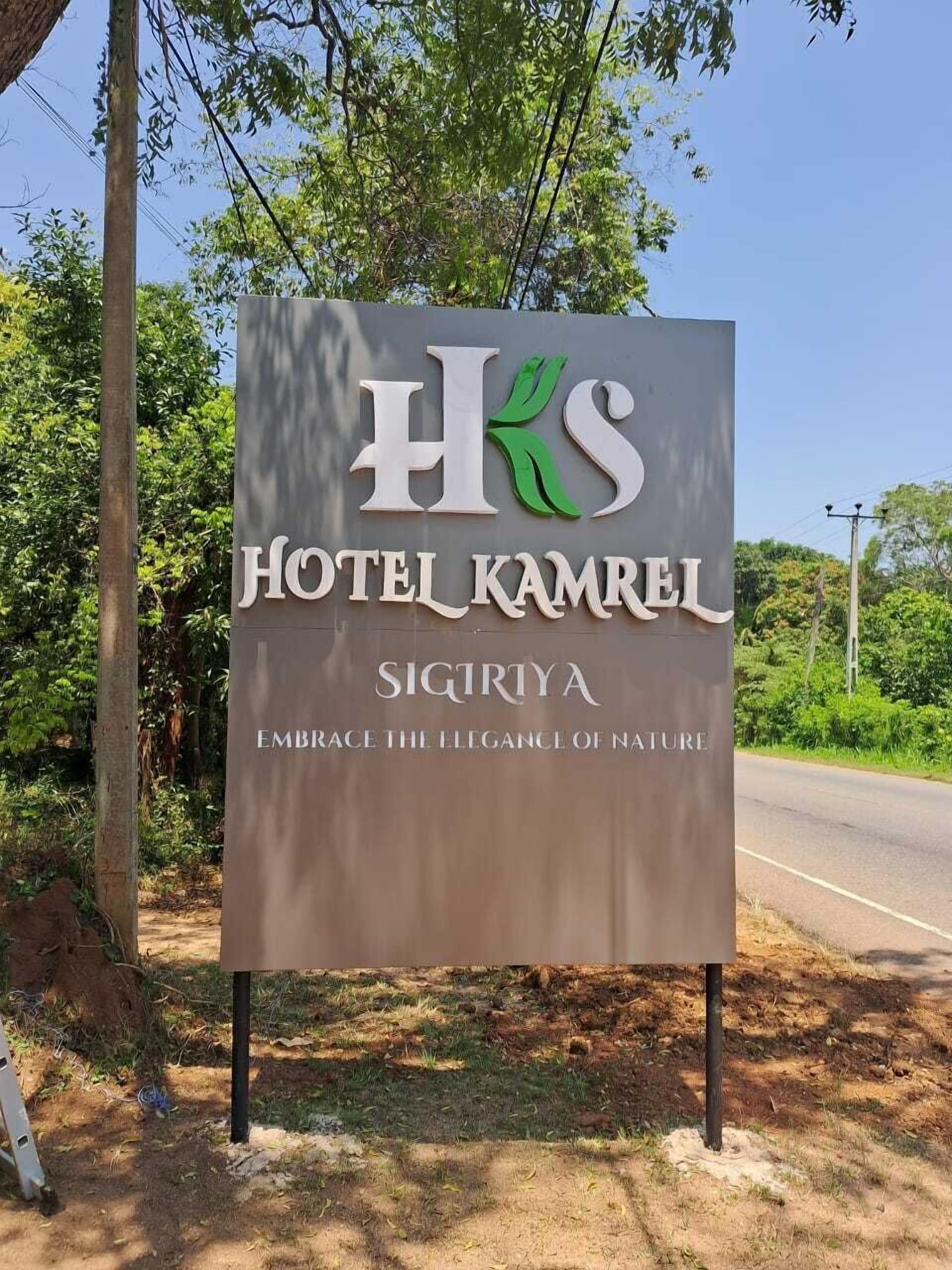 Un letrero del Hotel Kamrel con el nombre 'SIGIRTYA' y el lema 'ABRAZA LA ELEGANCIA DE LA NATURALEZA'.