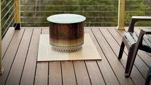 Una terraza de madera con una mesa redonda y un banco, con vistas a un paisaje montañoso.