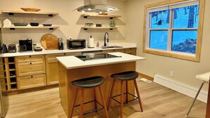 Una cocina moderna con una isla central, armarios de madera y una ventana con vistas nevadas.