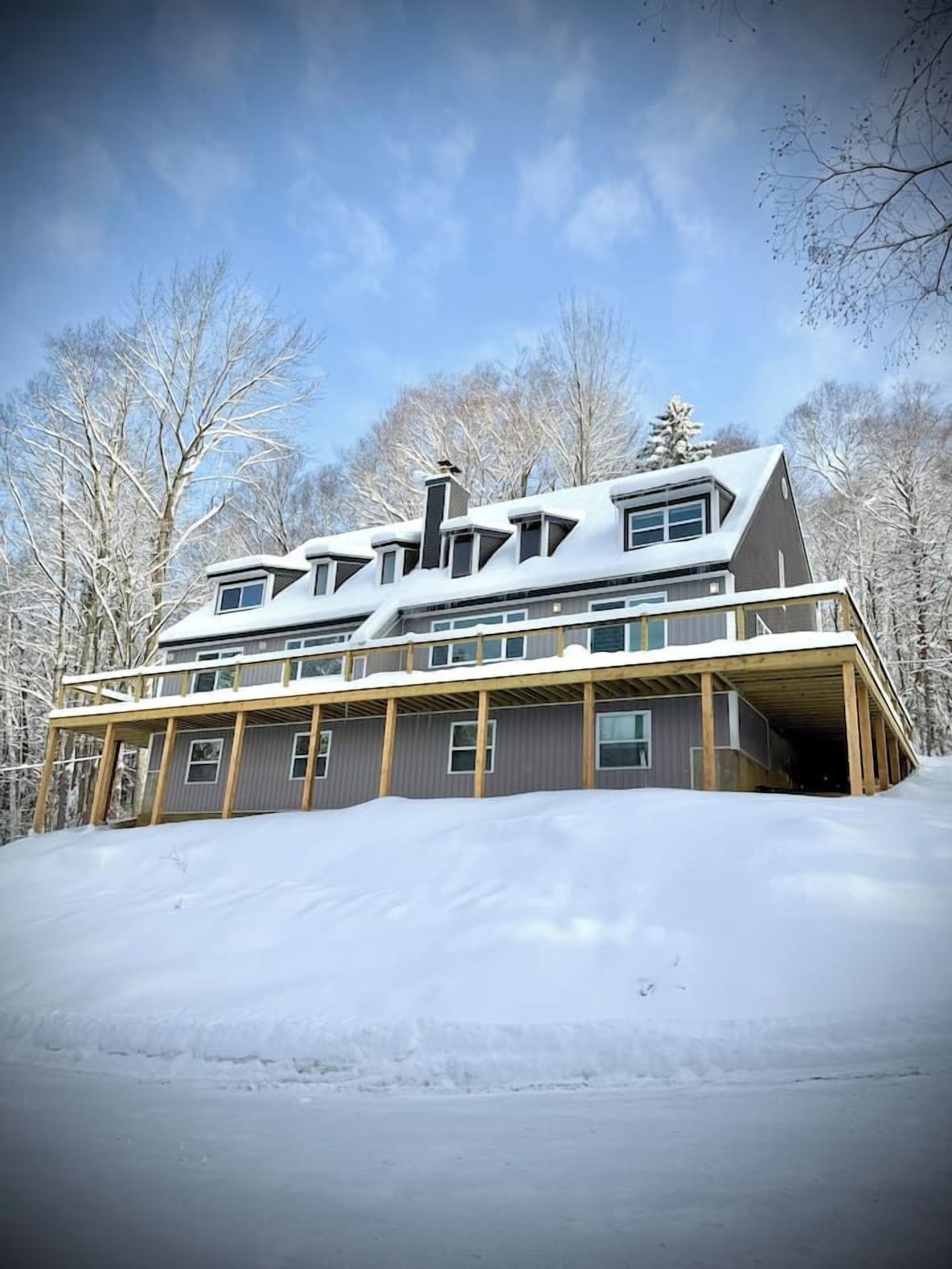 A two-story house with a sloped roof, large windows, and a covered porch.