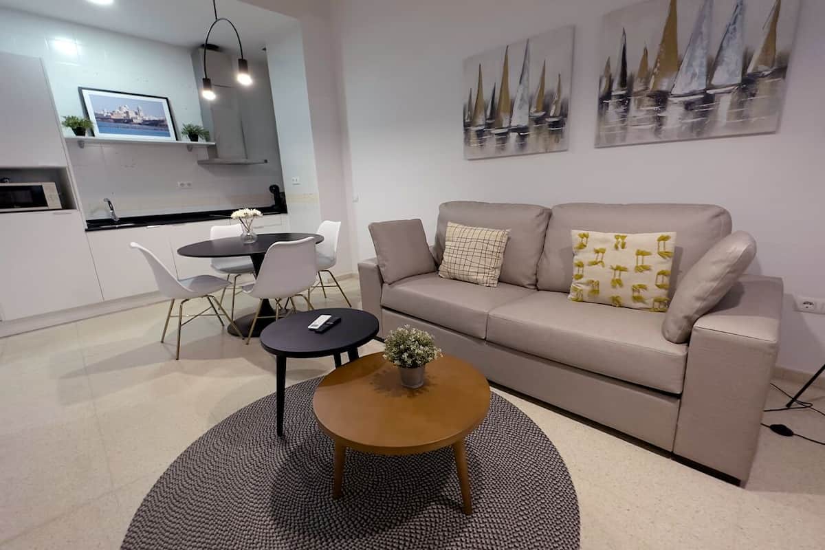 Un salon moderne avec un canapé beige, une table basse ronde et un coin repas comprenant une petite table et des chaises.