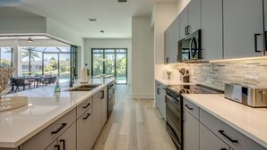 A modern kitchen with a large island, stainless steel appliances, and a view to the outdoors. - Villa Sunrays -NEW 3-bedroom Villa with pool & spa (Cape Coral)