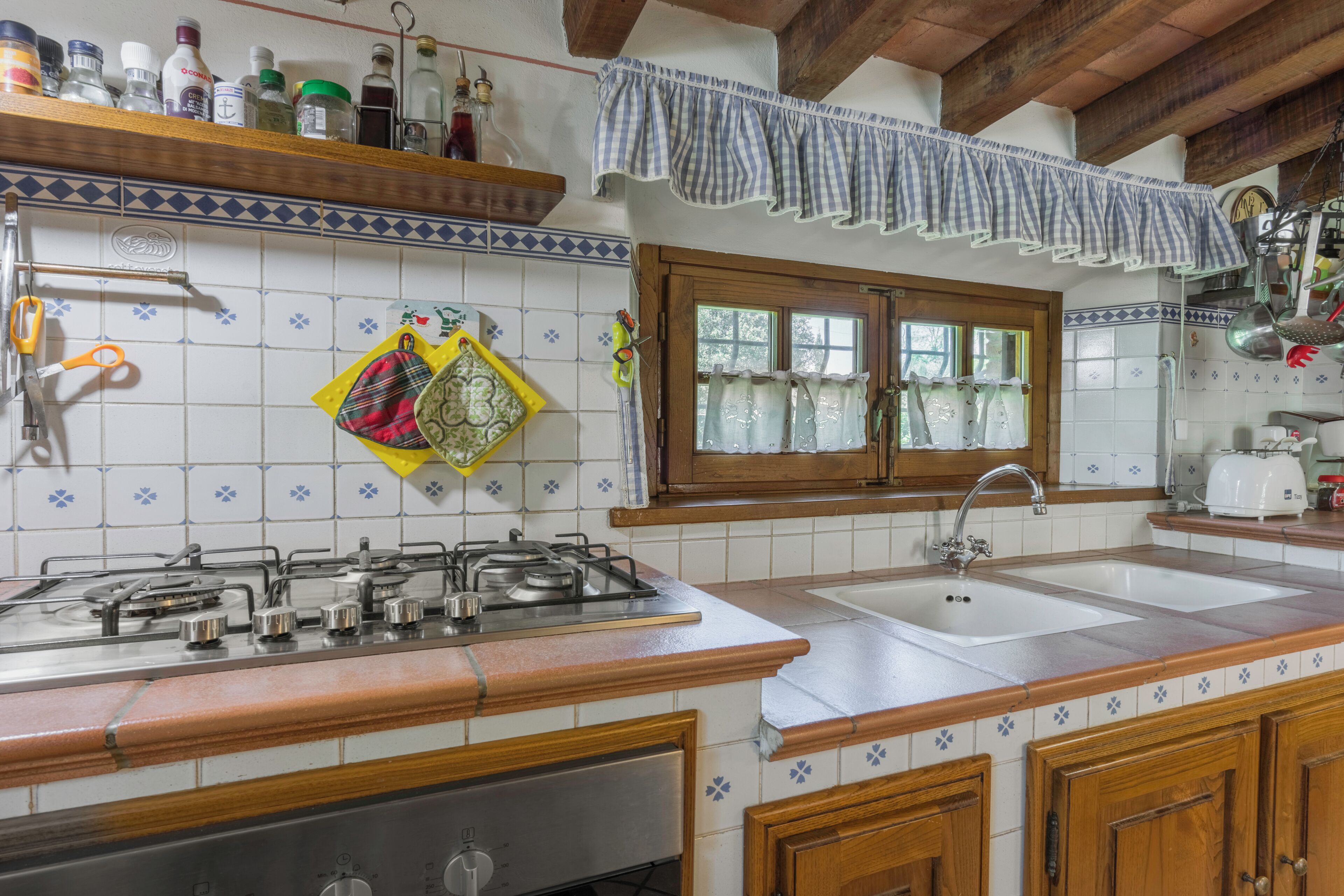 A kitchen with a gas stove, double sink, and wooden cabinets.