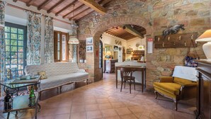 A rustic interior with a stone wall, wooden beams, a sofa, a table, and a chair. - Grace Home Pool Wifi Gambassi Terme (Gambassi Terme)