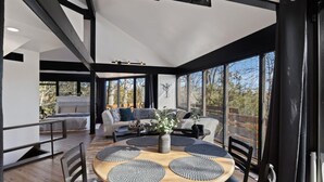 A modern interior with a round wooden table, black chairs, and a sofa with cushions.