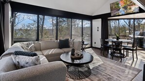 A modern living room with a sectional sofa, a round coffee table, and a dining area with chairs and a table.
