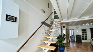 A staircase with wooden steps and a metal handrail, leading to a room with a tiled floor and a potted plant. - Le Ferney - Close to downtown and the spa (Rochefort)