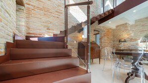 Una escalera con barandas de vidrio que conduce a una habitación con una mesa de comedor y sillas.