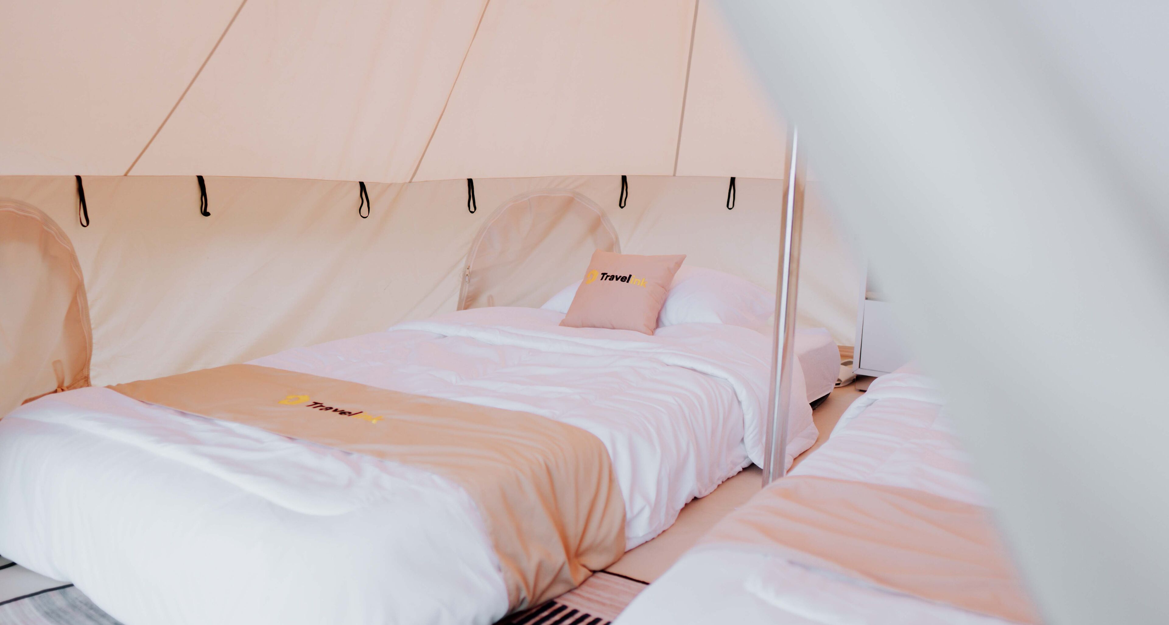 Een kamer met twee bedden, elk met een hemelbed en een kussen met een logo.